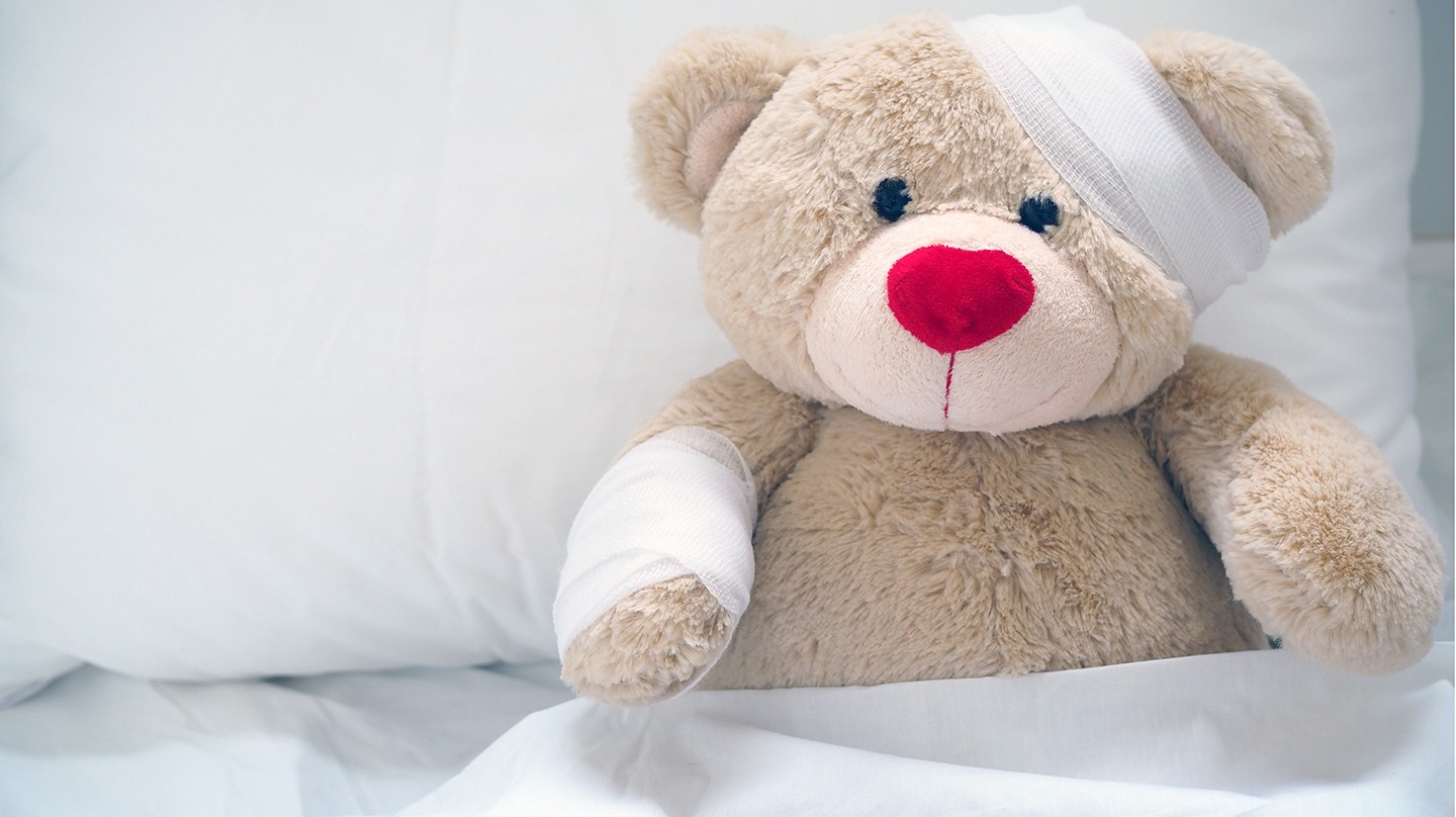 Erste Hilfe bei Kindern: Jeder 2. weiß nicht was zu tun ist Erste Hilfe bei Kindern: Ein Teddybär ist im Bett und hat einen Verband um seinen Kopf.