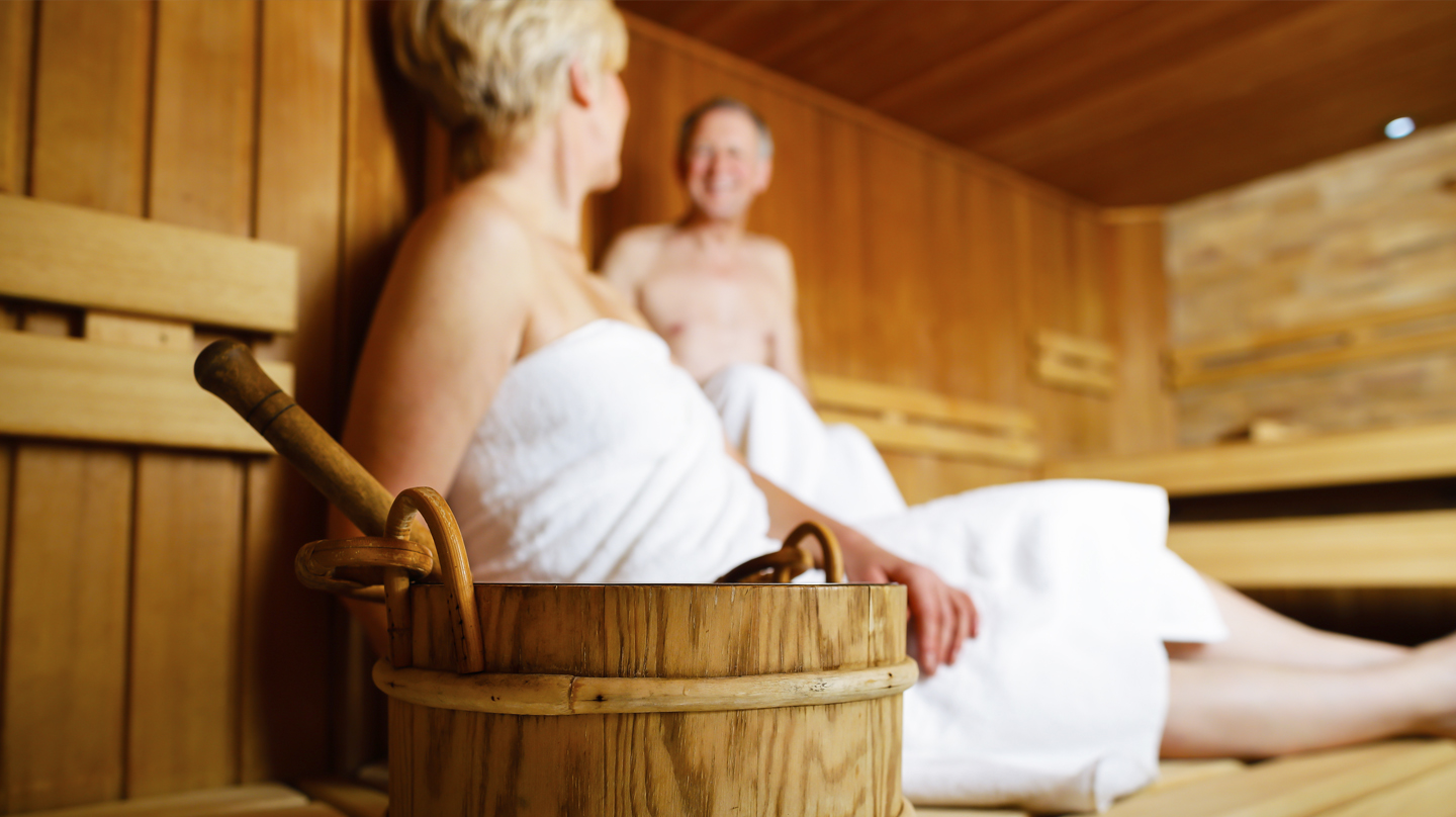 Richtig saunieren – Tipps für den Saunagang Richtig saunieren: Älteres Ehepaar in weiße Handtücher gehüllt in der Sauna.