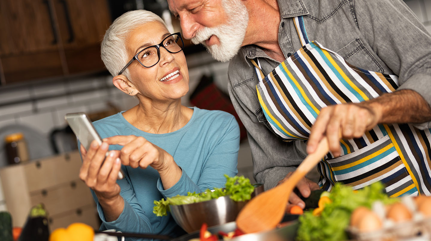 Diabetes – gesund abnehmen Gesund abnehmen: Älteres Pärchen beim Kochen in der Küche, im Vordergrund eine Salatschüssel.